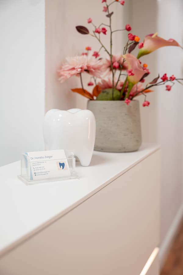 Ein Blumenstrauß ud Visitenkarten an der Rezeption der Zahnarztpraxis Dr. Horatio Zieger in Bonn