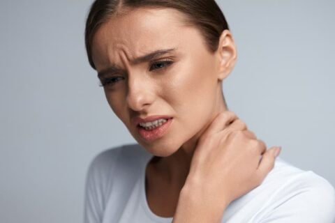 Frau hält ihre Hand an schmerzenden Nacken